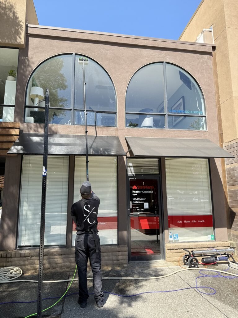 Water-fed pole cleaning a storefront facade